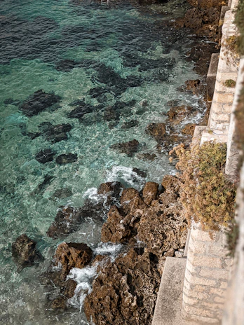 Turquoise waves gently lapping against ancient stone steps leading into the sea.