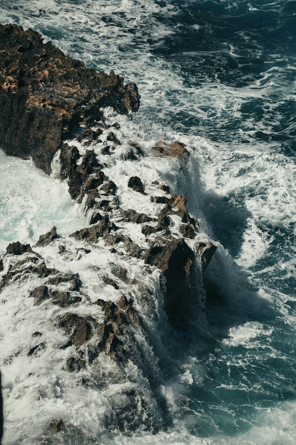 Una persona in piedi sulla cima di una scogliera rocciosa vicino all'oceano