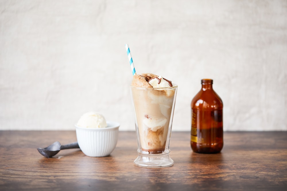 a glass of ice cream next to a bottle of beer