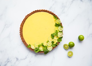 a pie with limes and lime slices on a marble surface