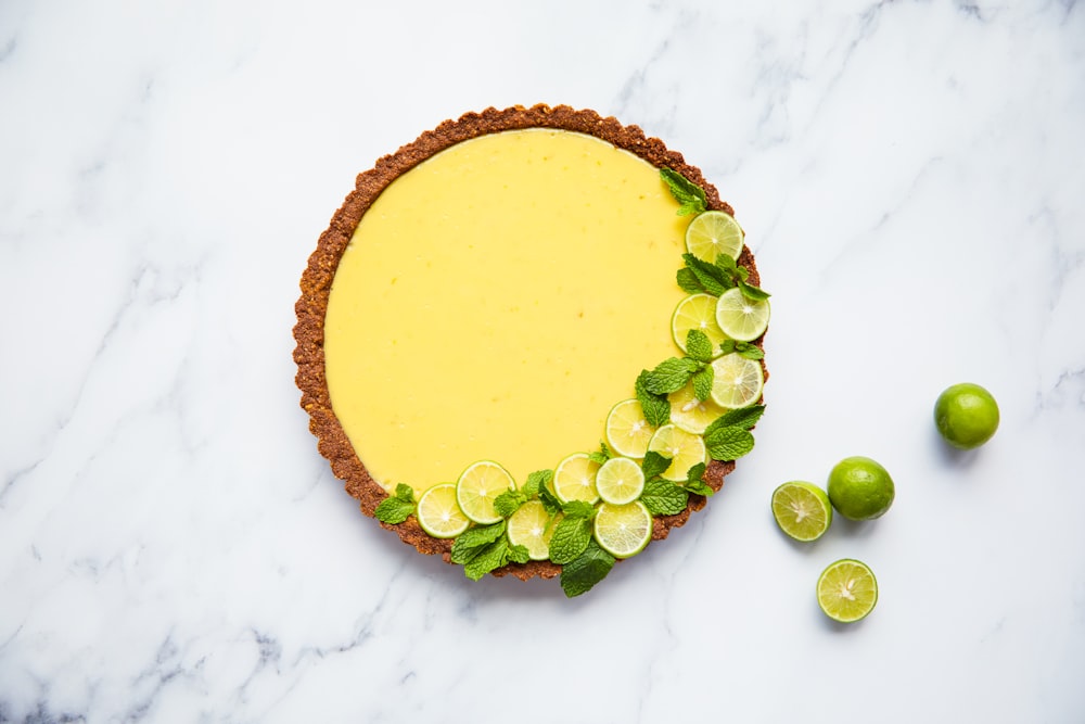 a pie with limes and lime slices on a marble surface