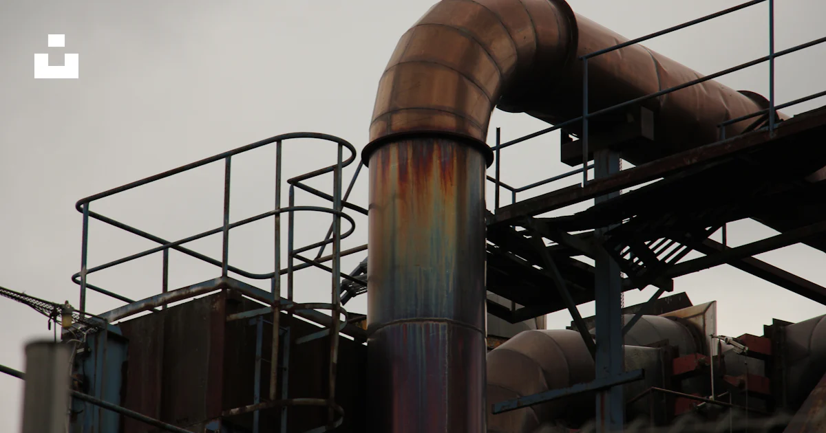 A metal pipe with rust on it near a building photo – Free Brown Image ...