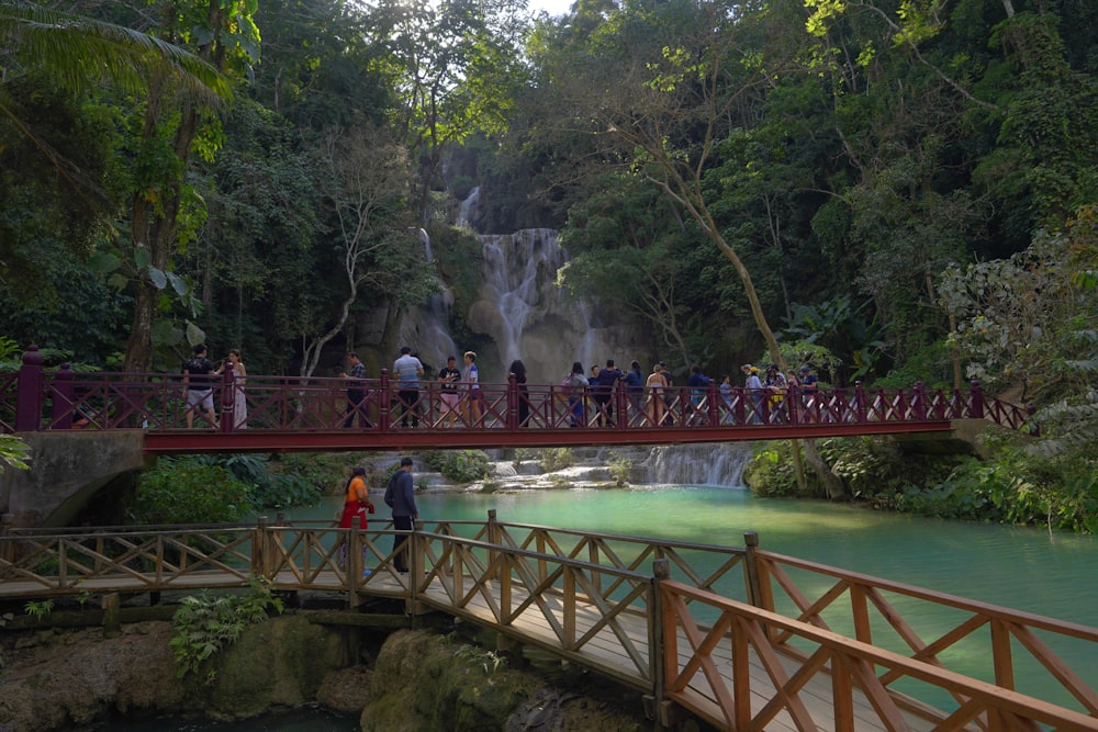 a group of people walking across a bridge over a river