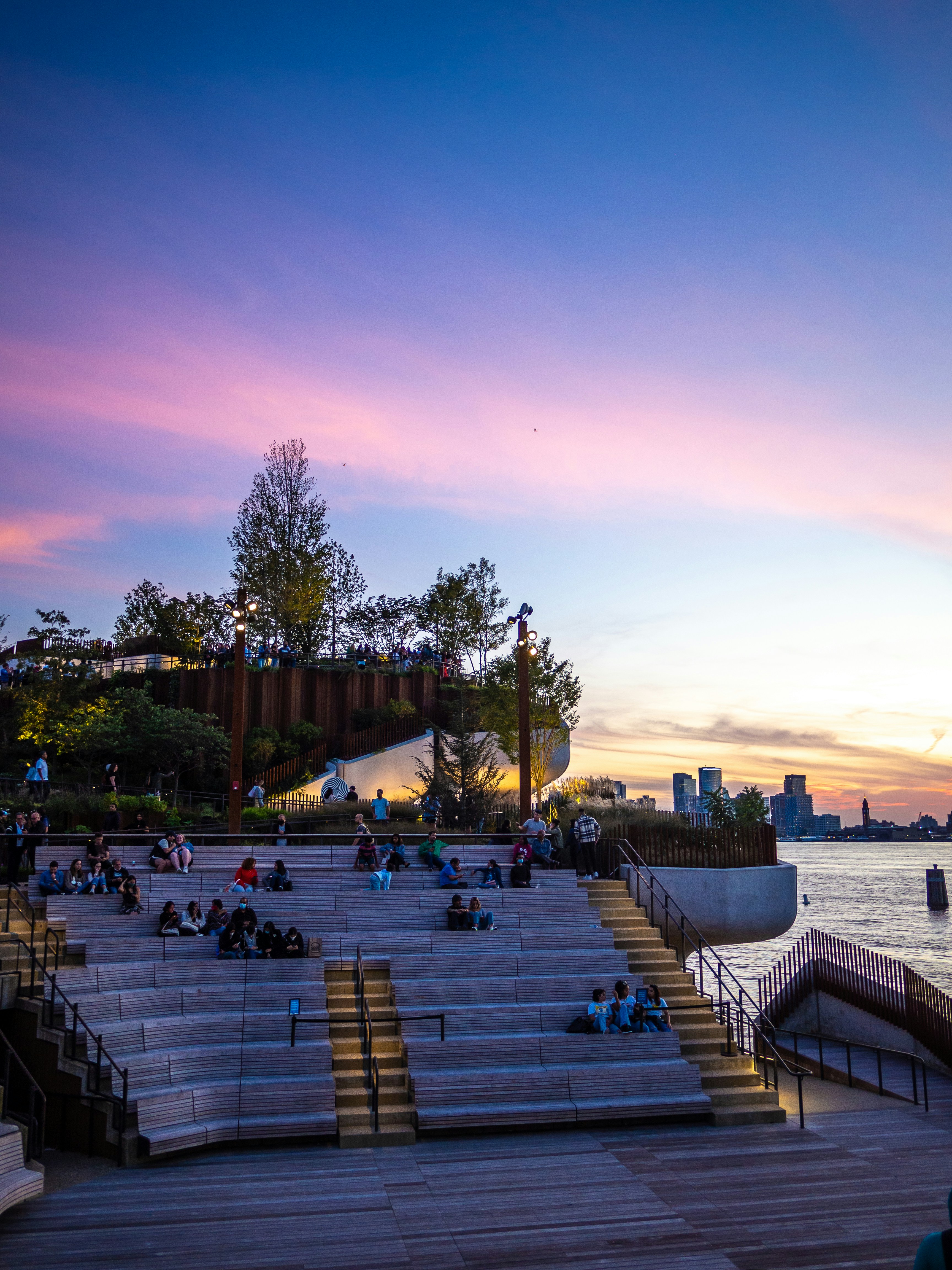 a group of people sitting on steps next to a body of water
