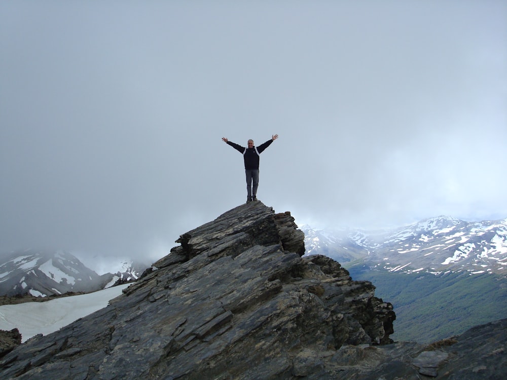 a man standing on top of a mountain with his arms wide open