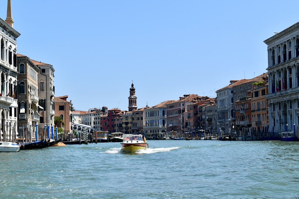 a boat traveling down a river next to tall buildings