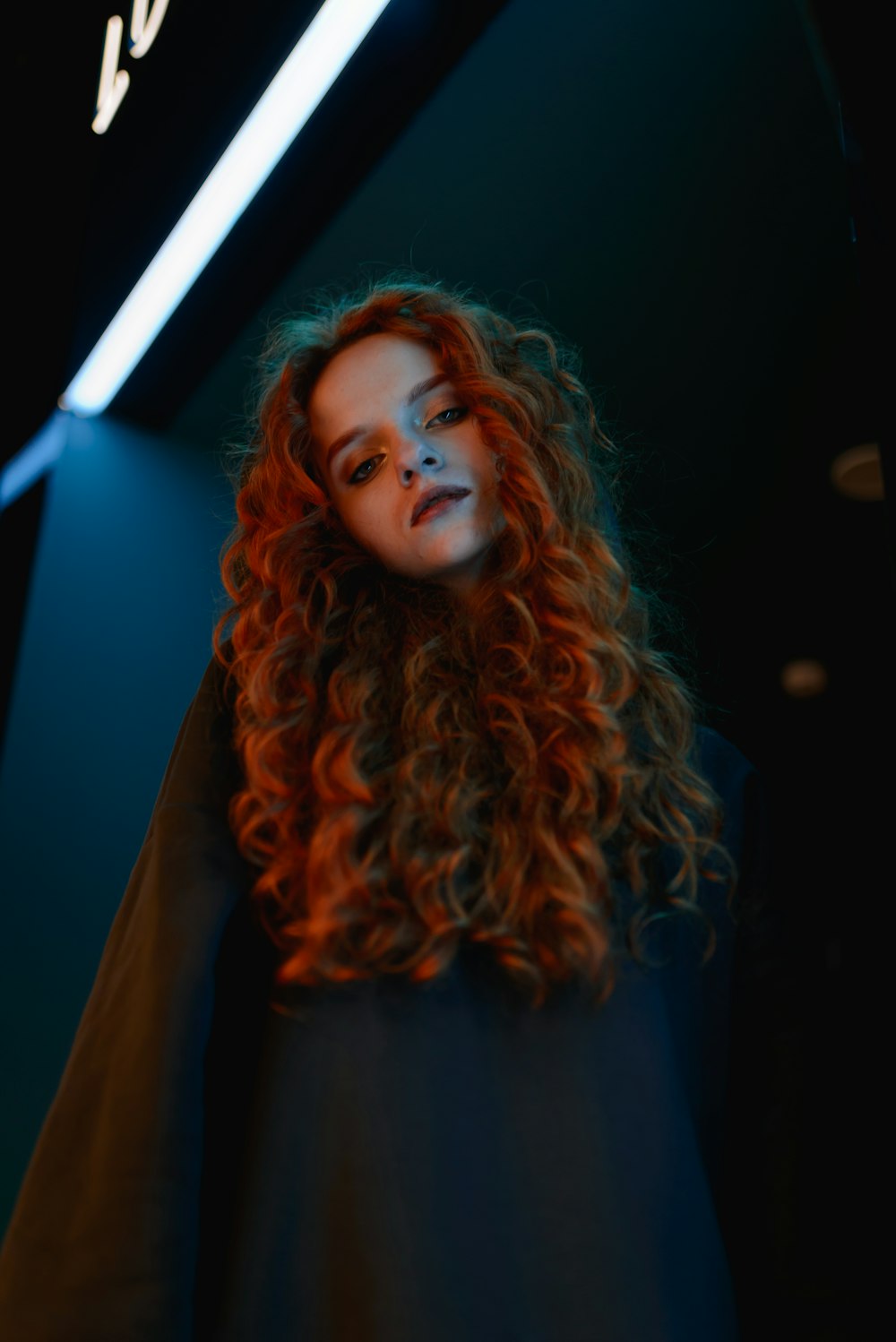 a woman with red hair standing in a dark room