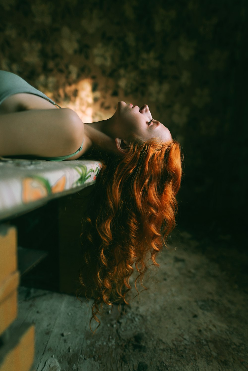 a woman with red hair laying on a bench