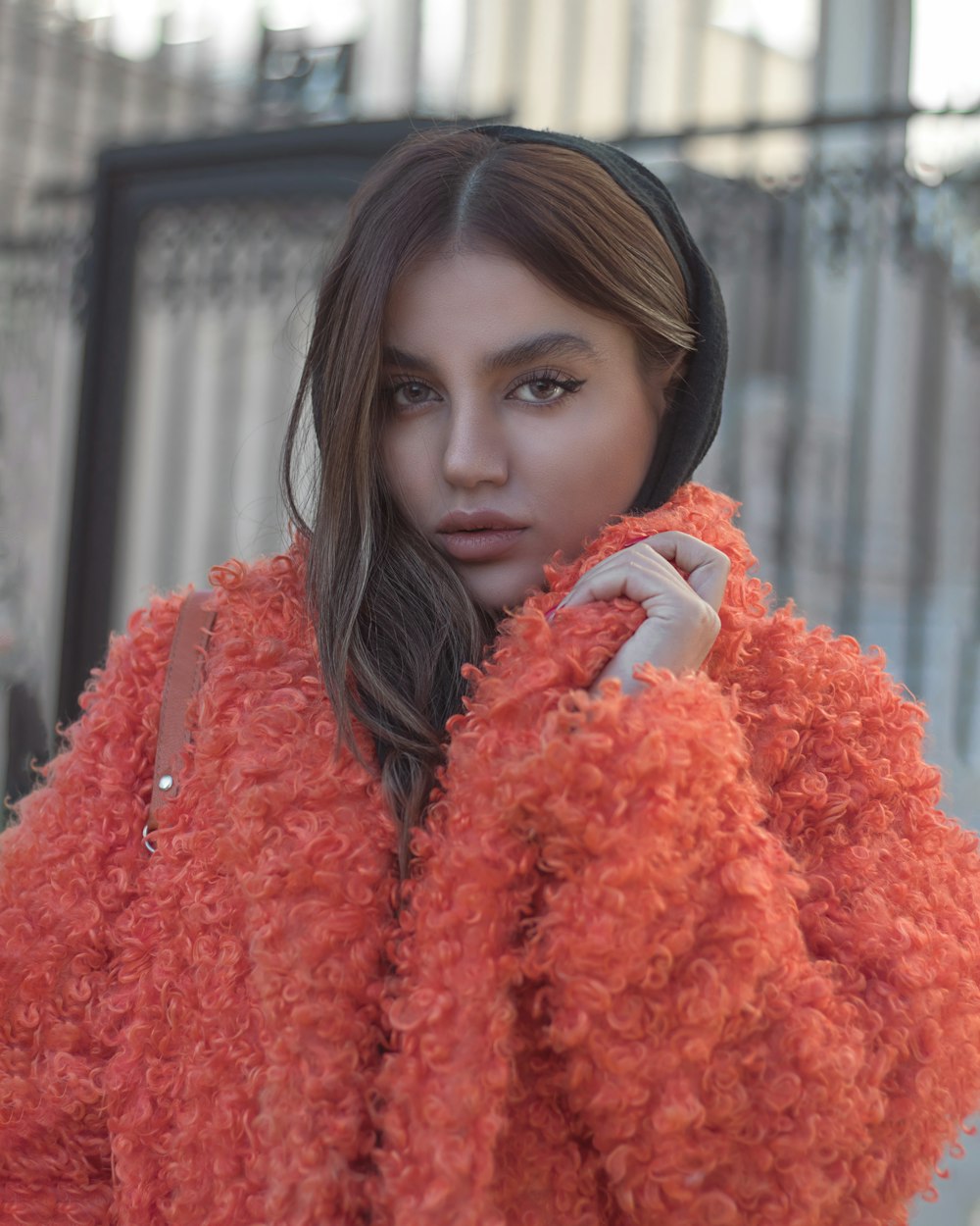 a woman in an orange coat is posing for a picture