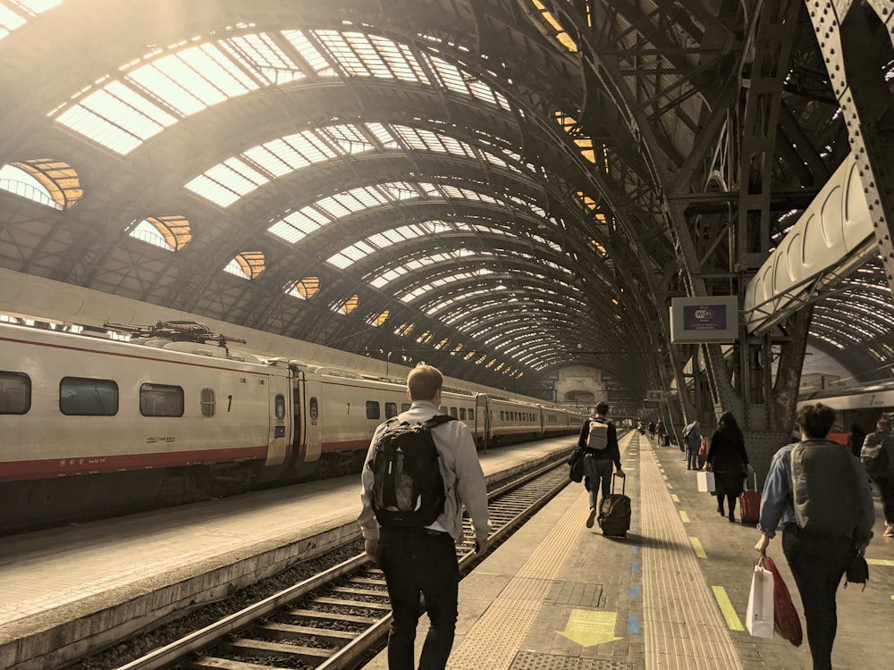 a group of people walking along side of a train station