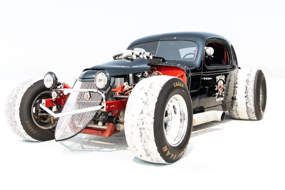 a black and red car with big tires on a white background