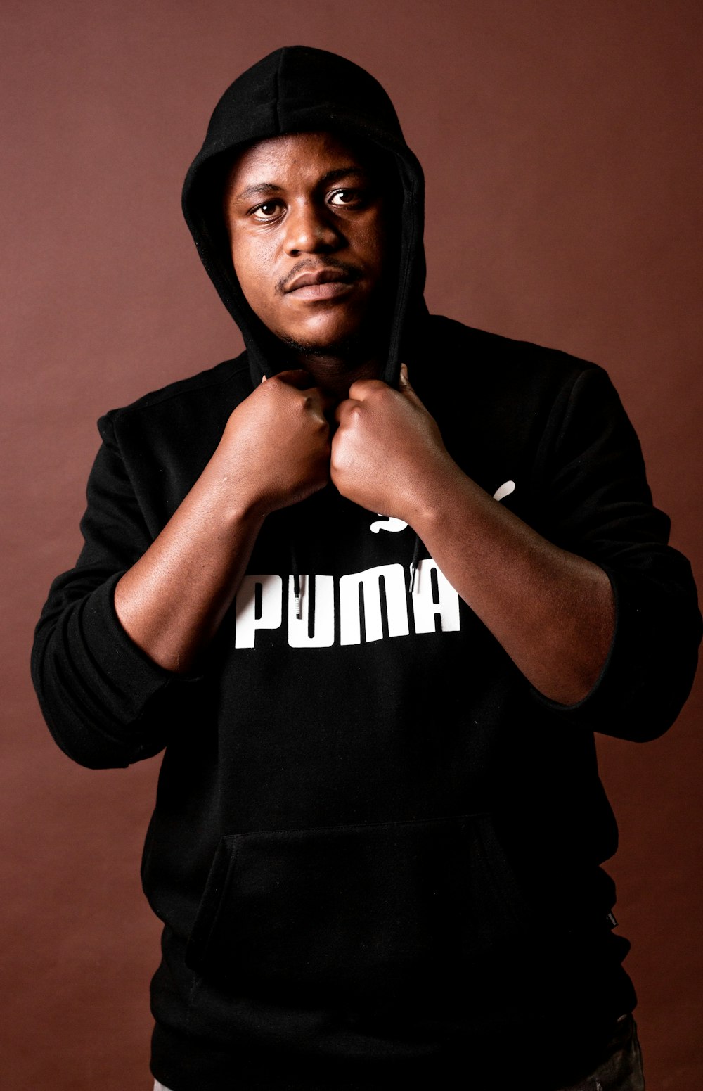 a man in a black hoodie poses for a picture