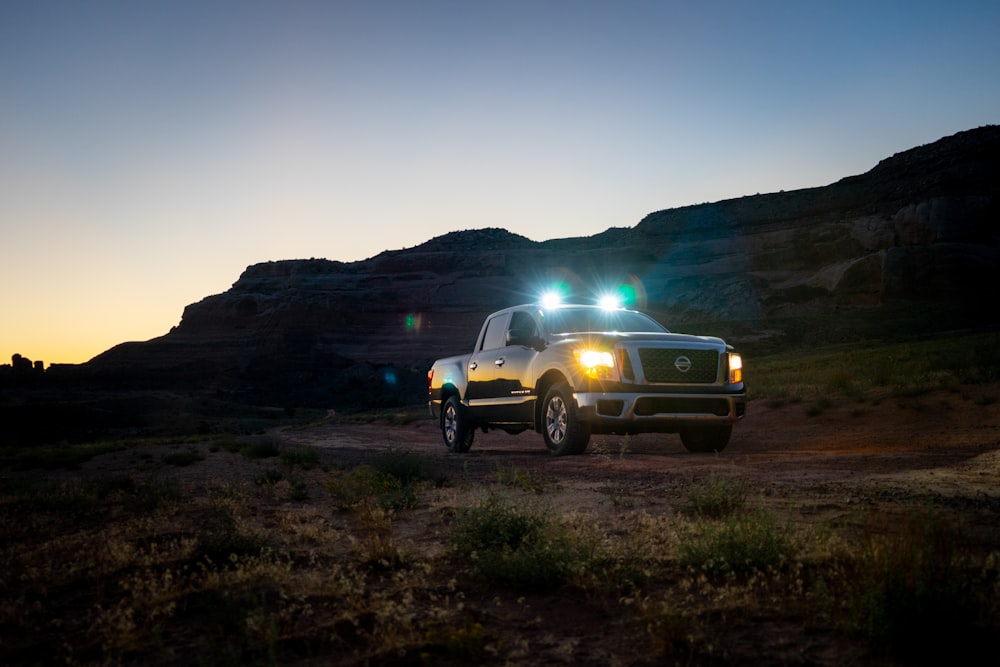 a white truck with two lights on driving down a dirt road