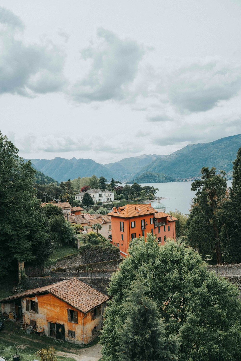 a view of a village with a lake and mountains in the background