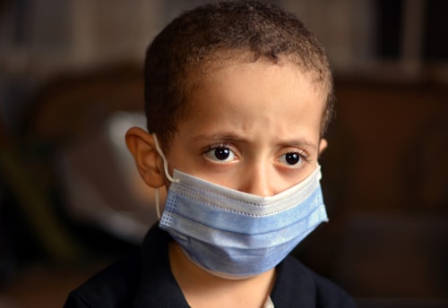 a young boy wearing a blue face mask
