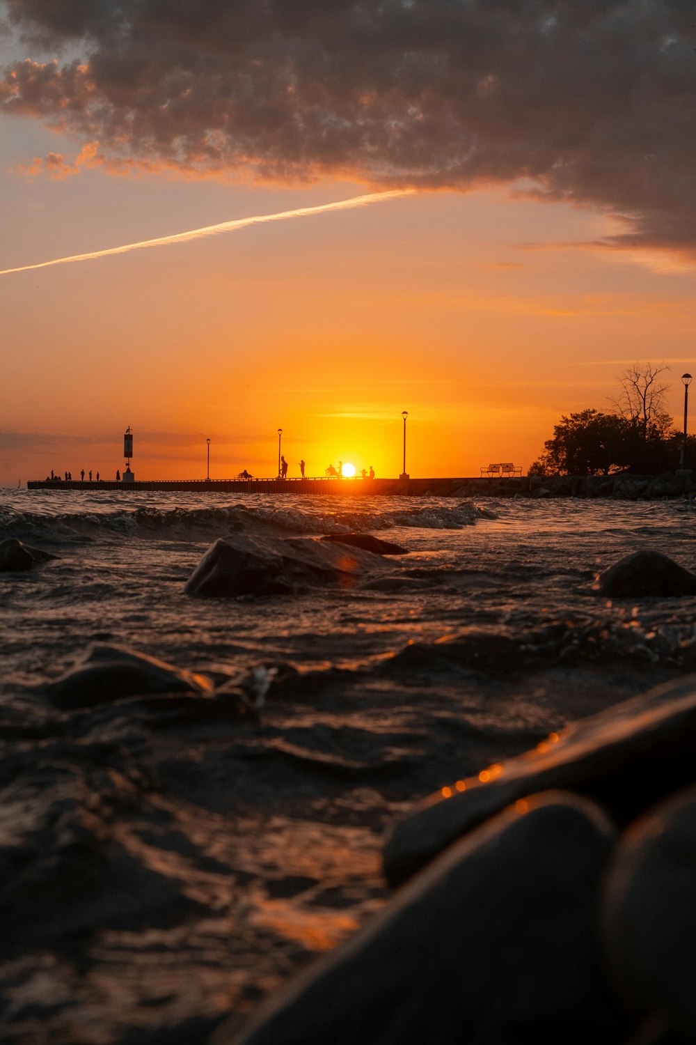 Ein Sonnenuntergang über einem Gewässer mit einem Leuchtturm in der Ferne