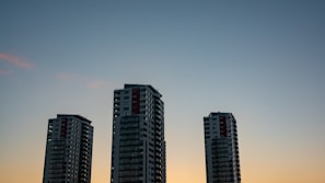 Sunlit view of the three elegant towers rising against a clear blue sky, highlighting the modern architecture.