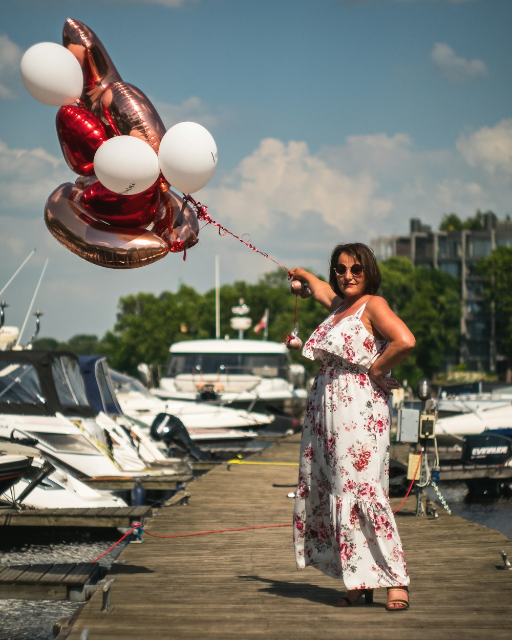 a woman in a white dress holding a bunch of balloons