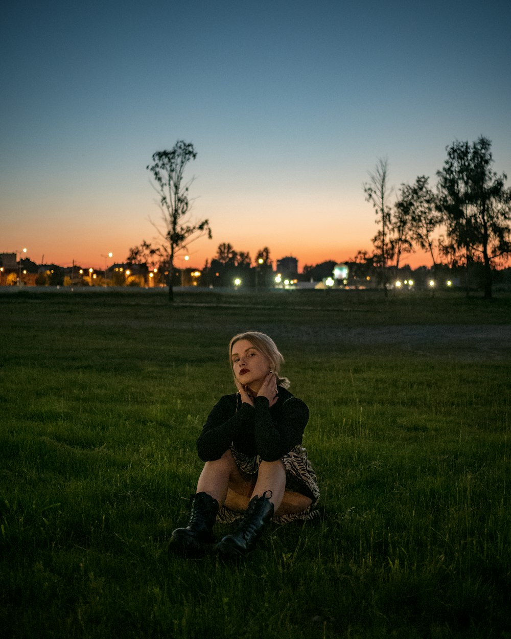 a woman sitting in the grass with her hand on her face