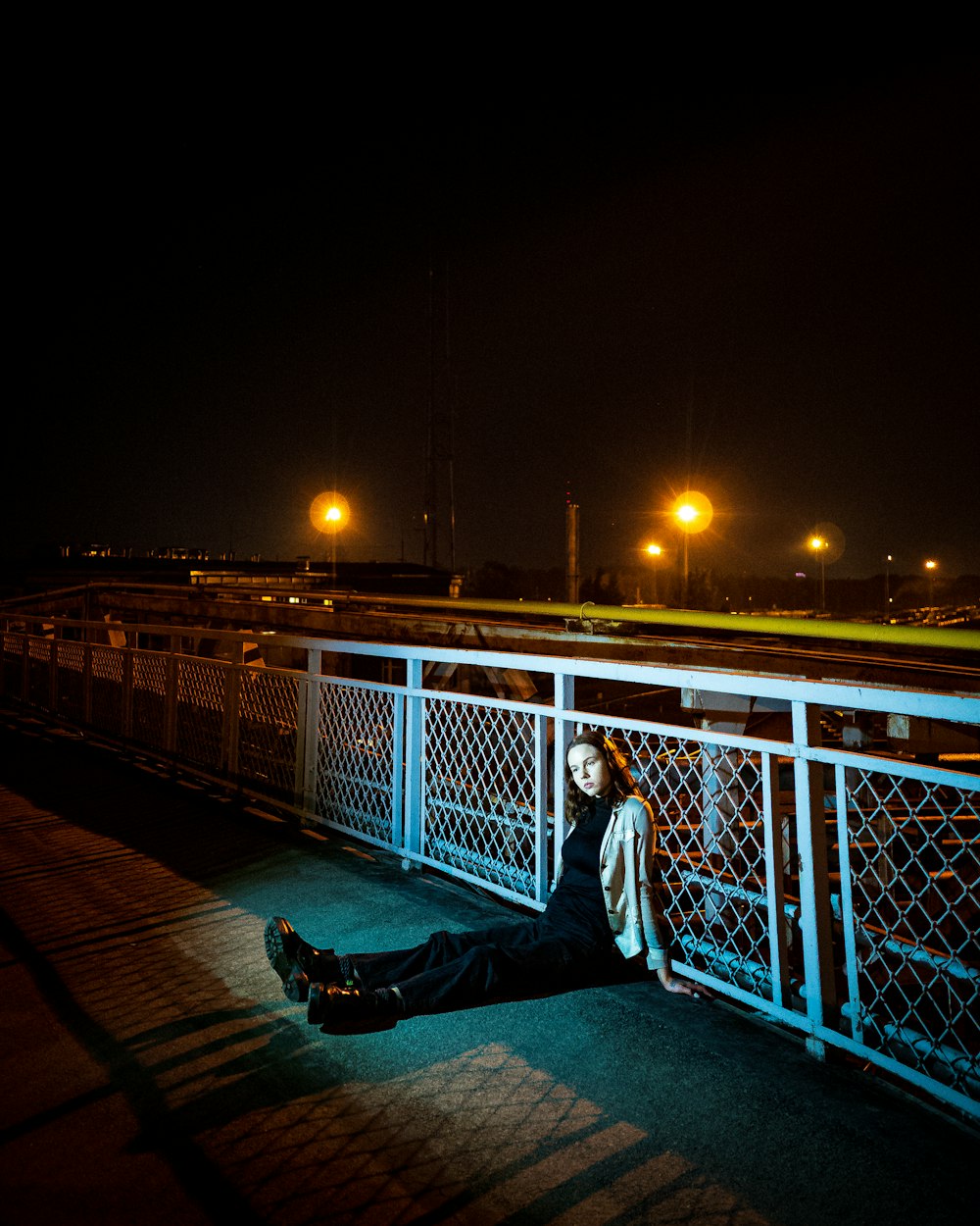 a woman sitting on a bridge at night