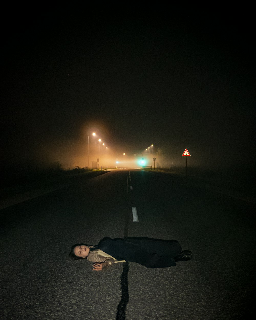 una persona acostada al costado de una carretera por la noche