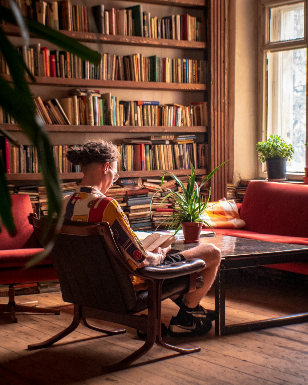 a man sitting in a chair in front of a book shelf