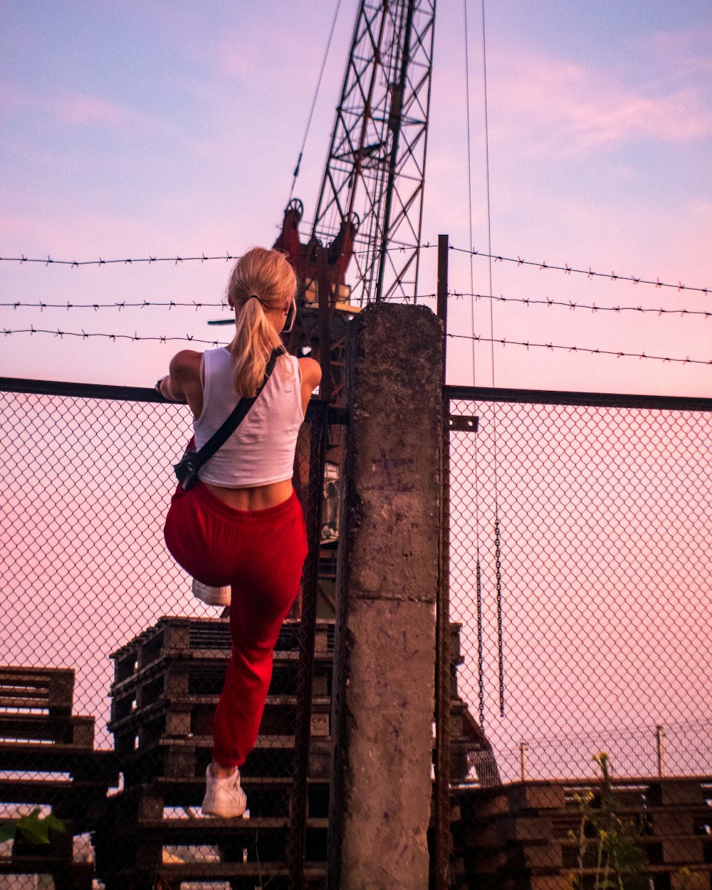 a woman climbing up the side of a fence