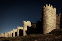 a castle like structure on a hill with a dark sky in the background