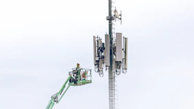 Technicians working on telecommunications towers with safety harnesses.