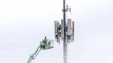 Technicians working on telecommunications towers with safety harnesses.