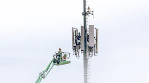 Technician inspecting Corronite earthing setup at a telecom tower with electric blue accents.