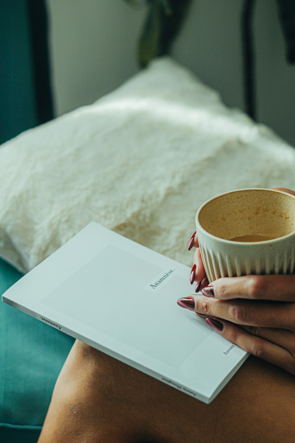 a woman sitting on a bed holding a cup of coffee