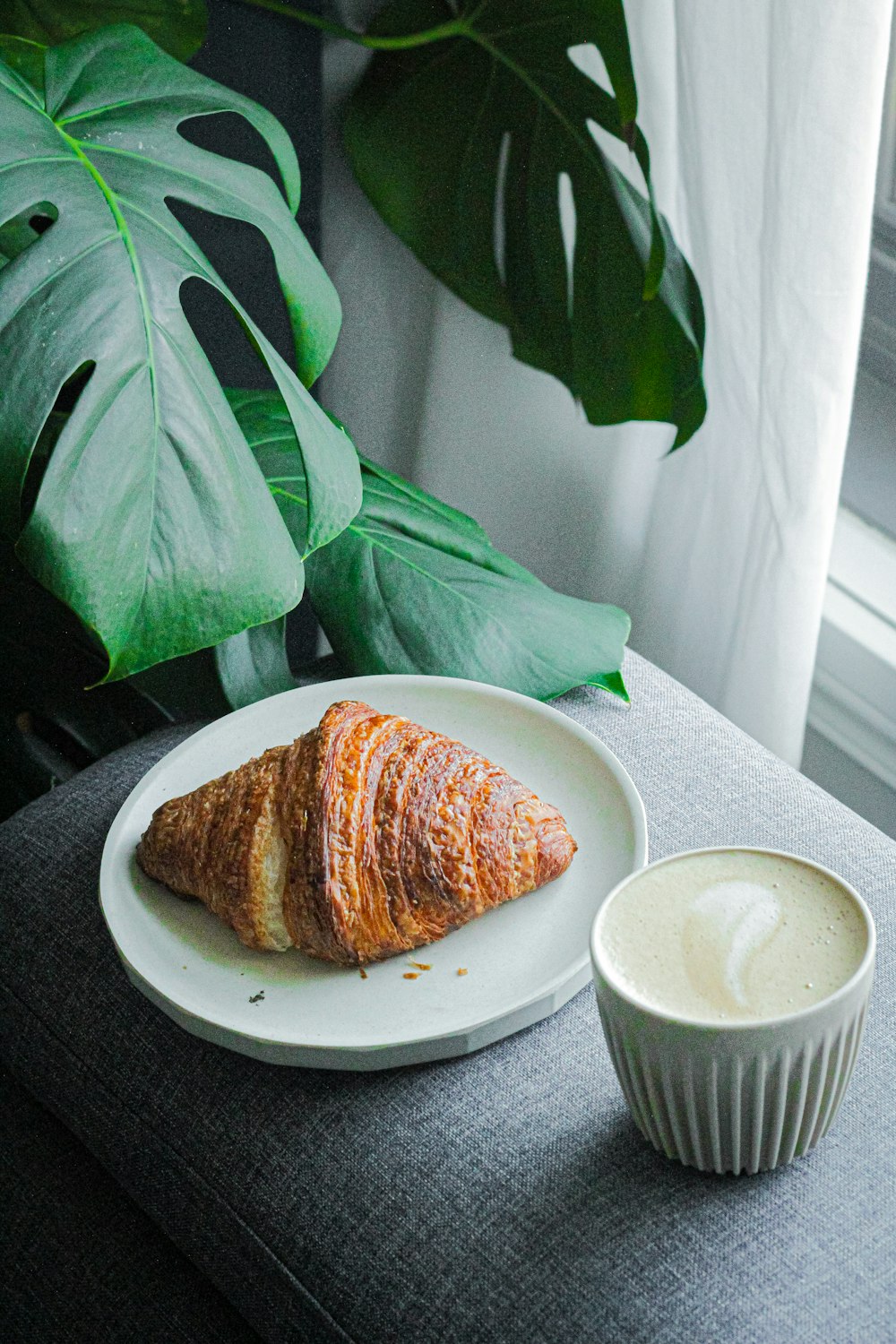 a white plate topped with a pastry next to a cup of coffee