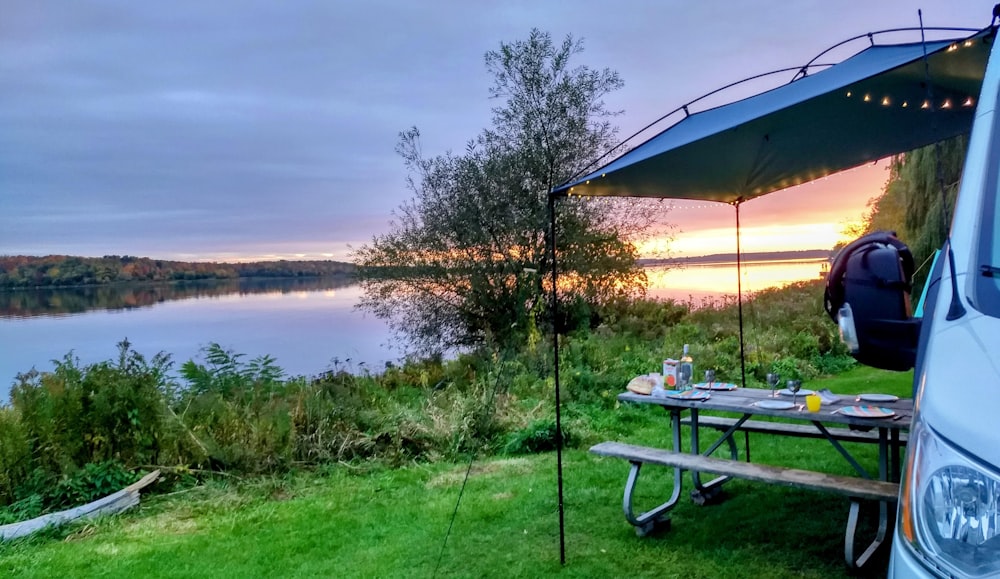 a camper van parked next to a lake at sunset