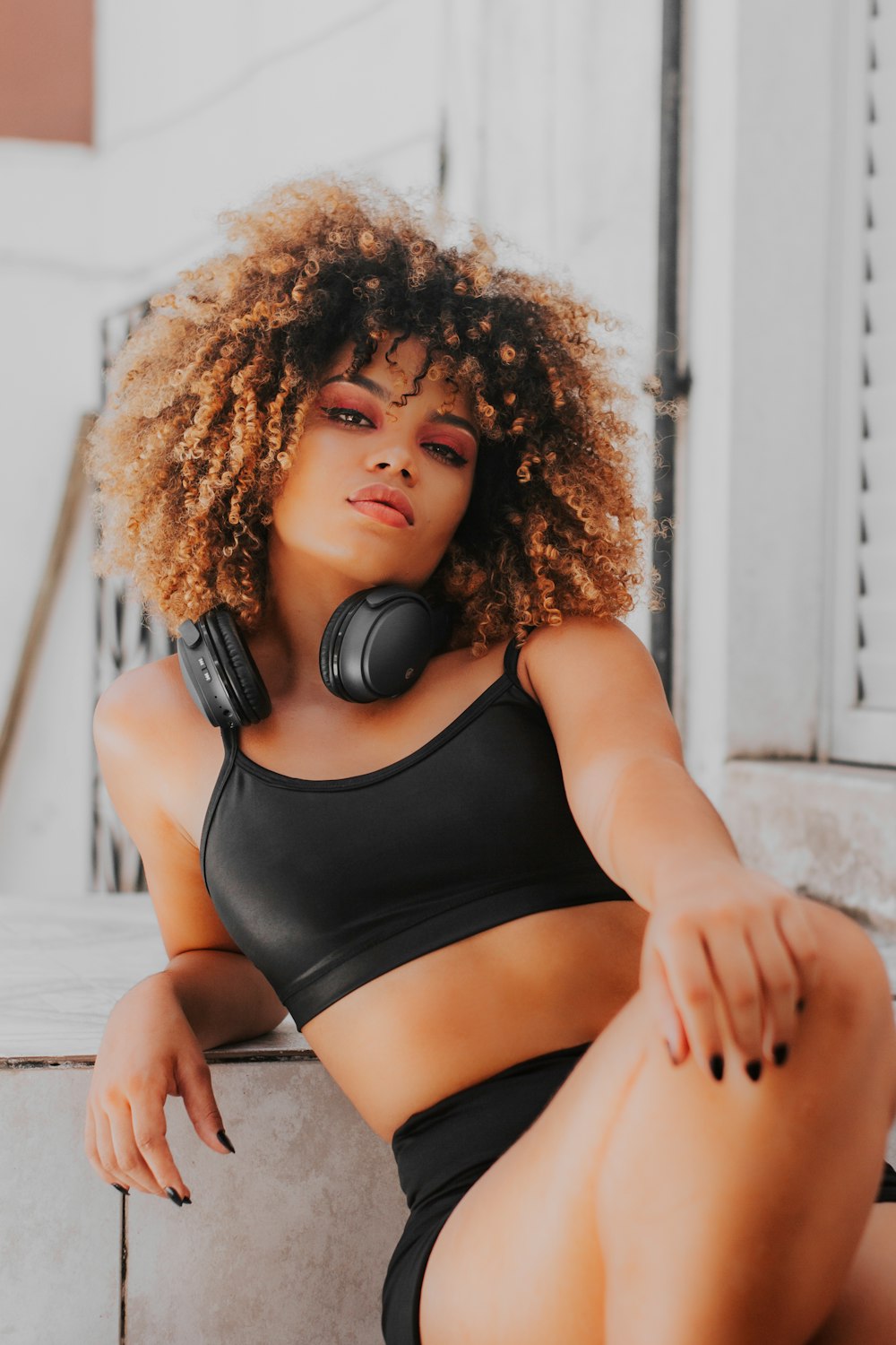 a woman wearing headphones sitting on a ledge