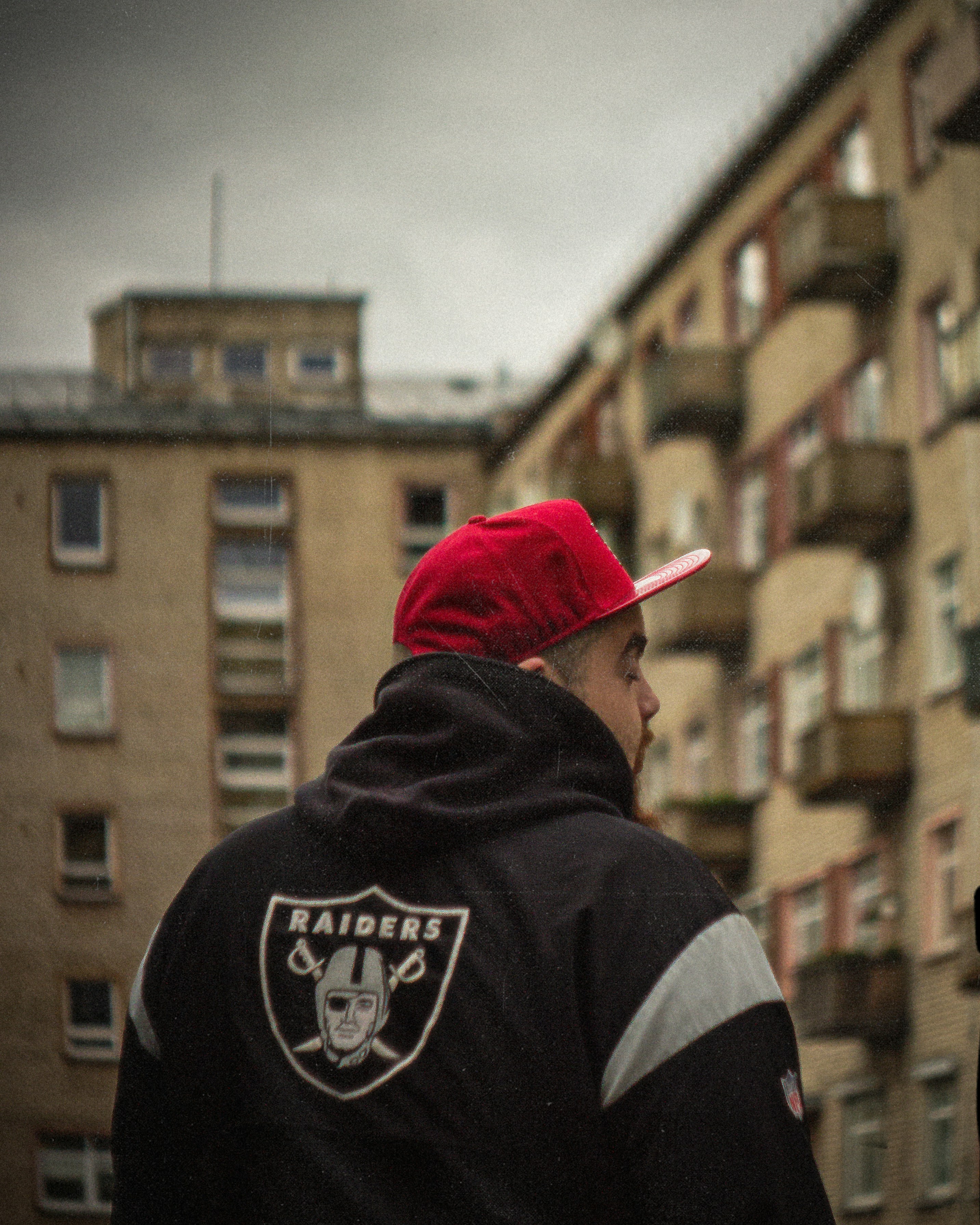 a man in a red hat is standing in front of a tall building