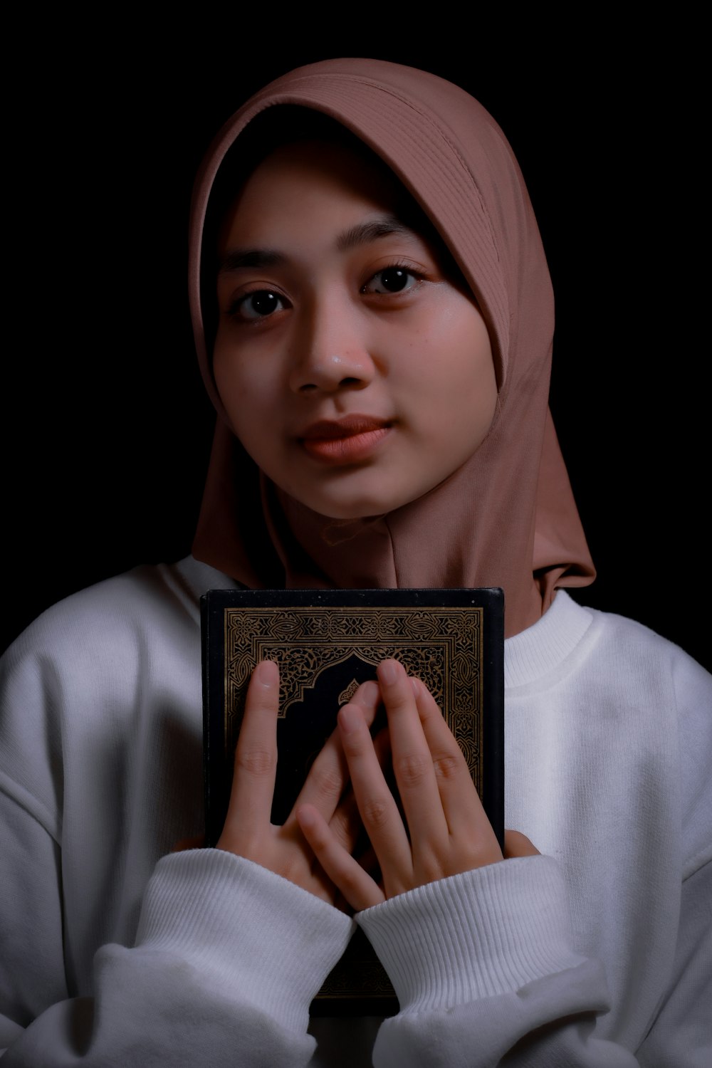 a woman in a hijab holding a book