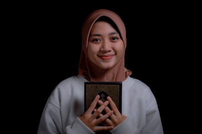 a woman wearing a headscarf holding a book