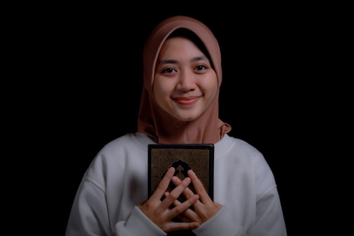 a woman wearing a headscarf holding a book