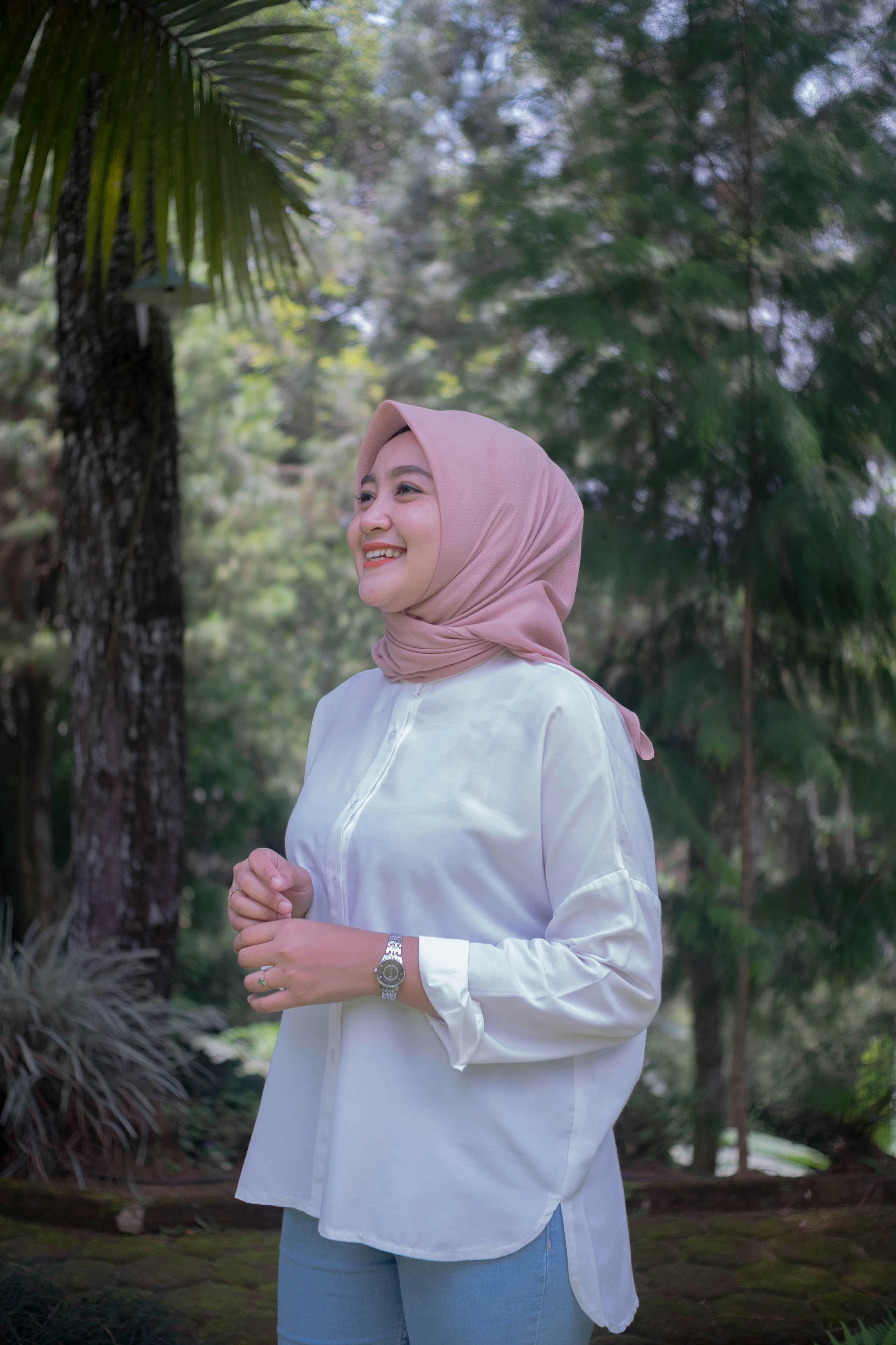 a woman standing in front of a tree wearing a headscarf