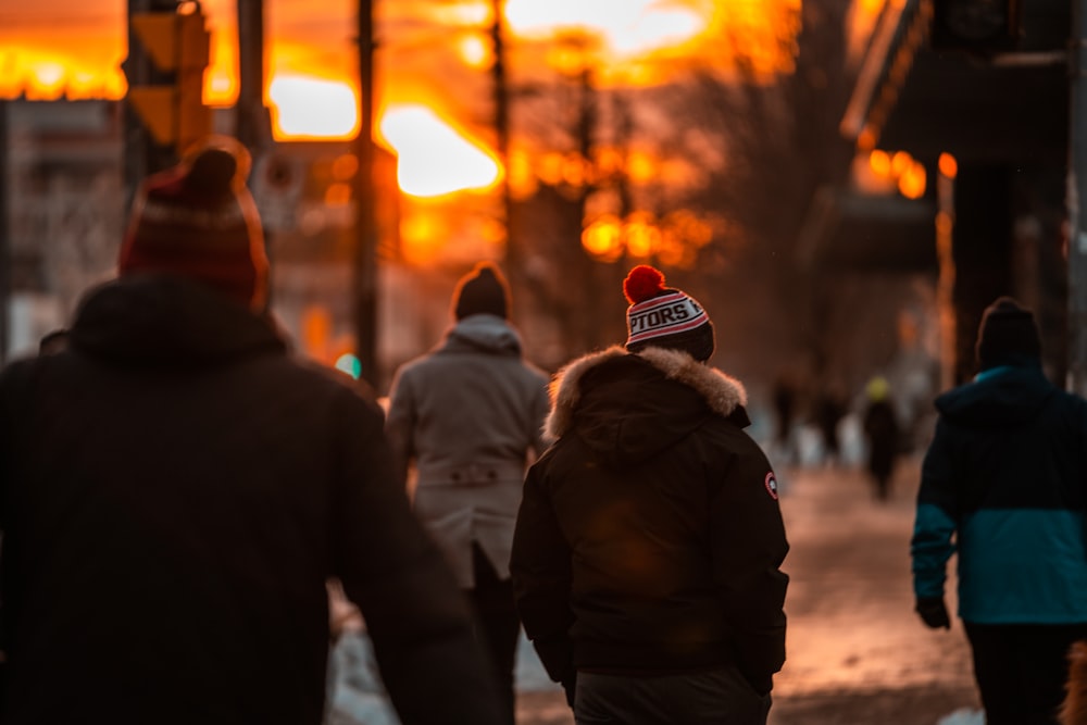 a group of people walking down a street at sunset