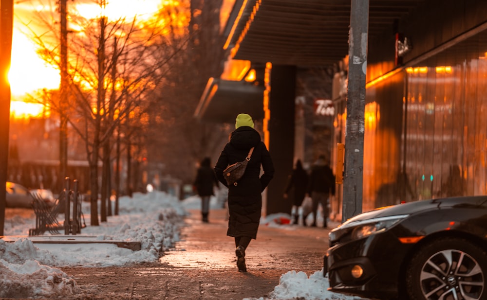 a person walking down a sidewalk in the snow
