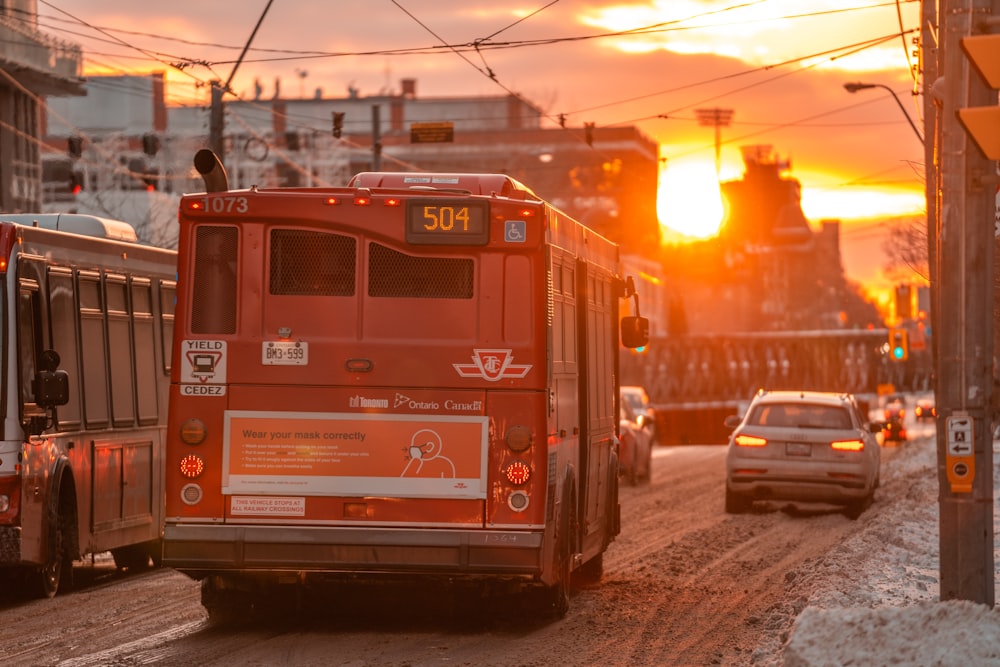 a red bus driving down a street next to a traffic light