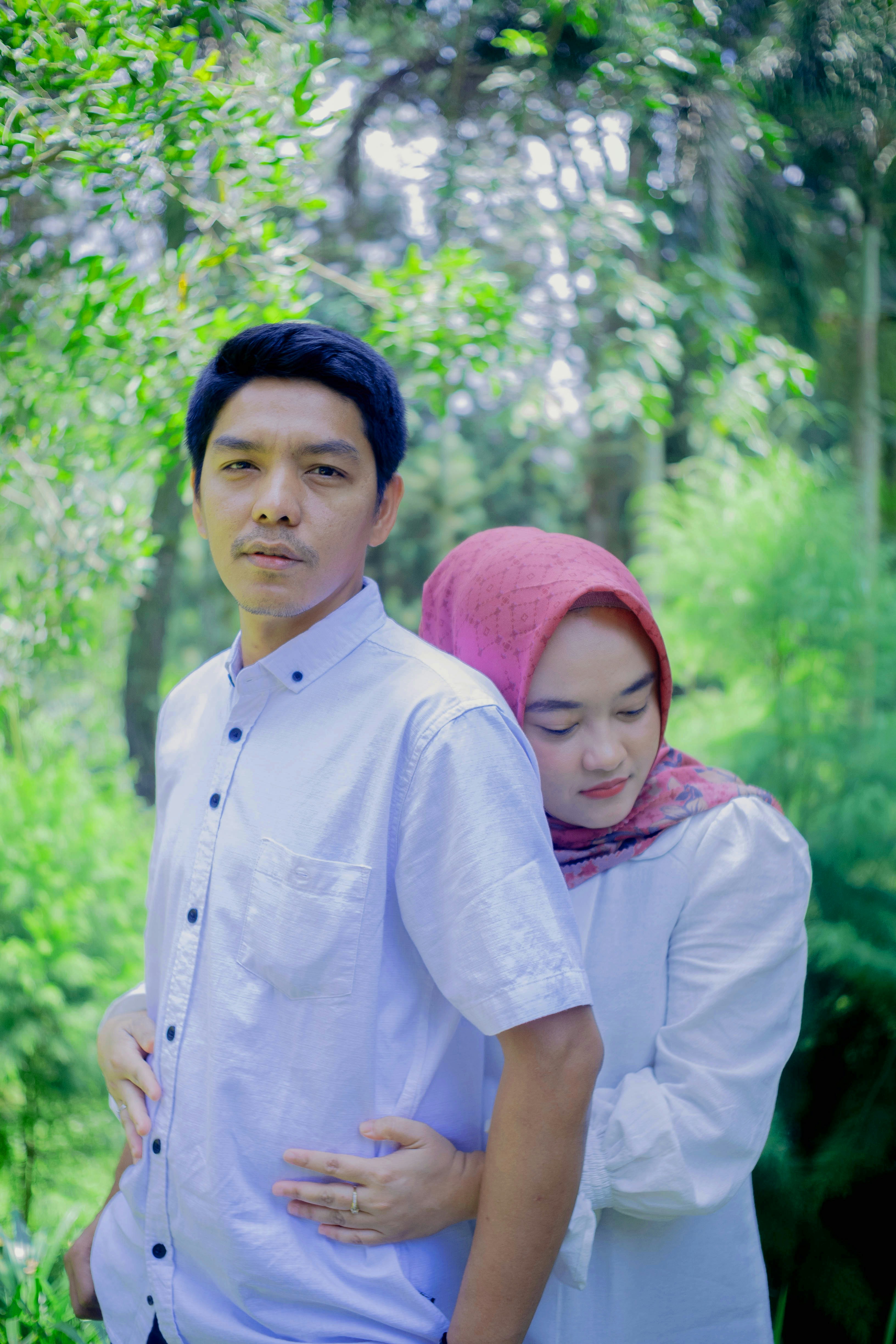 a man and a woman standing together in the woods