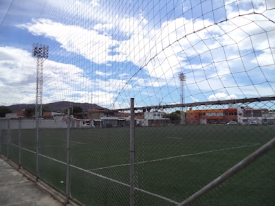 A soccer field secured with sturdy metal fencing under daylight.