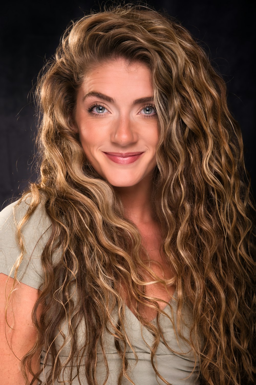 a woman with long curly hair and a smile on her face