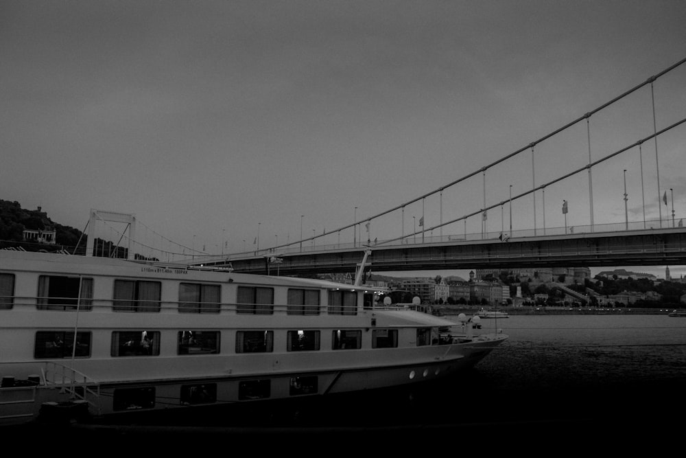 a large boat floating on top of a river under a bridge