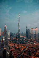 The Burj Khalifa tower rising above the illuminated skyline and highway interchange in Dubai