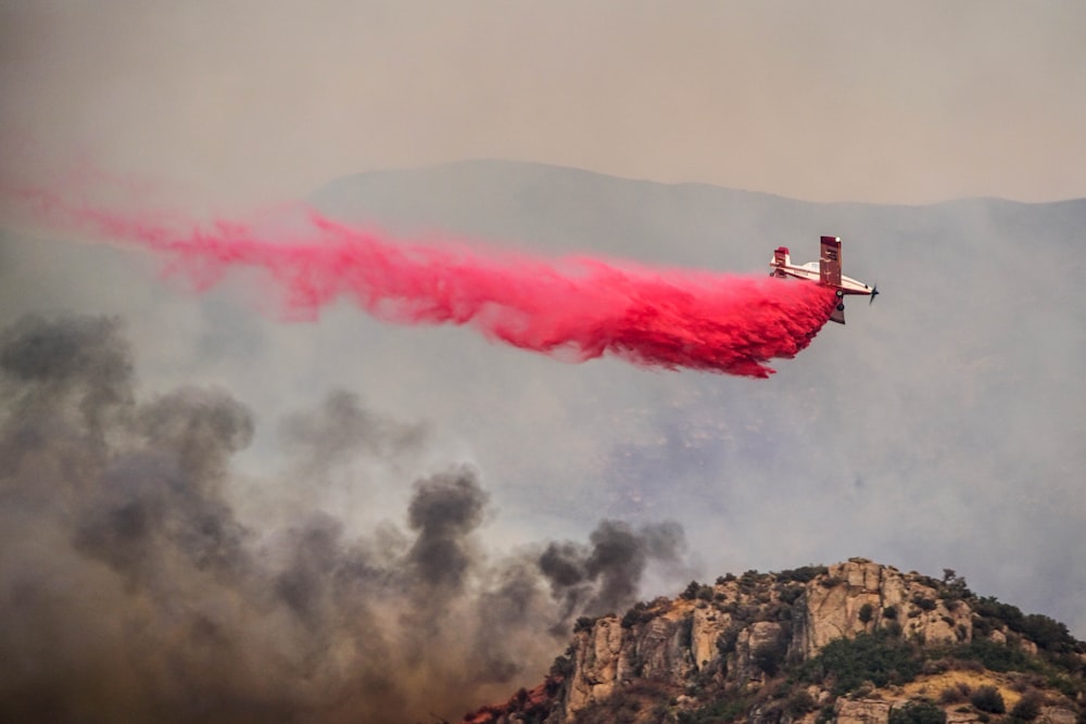 a red plane is flying over a mountain