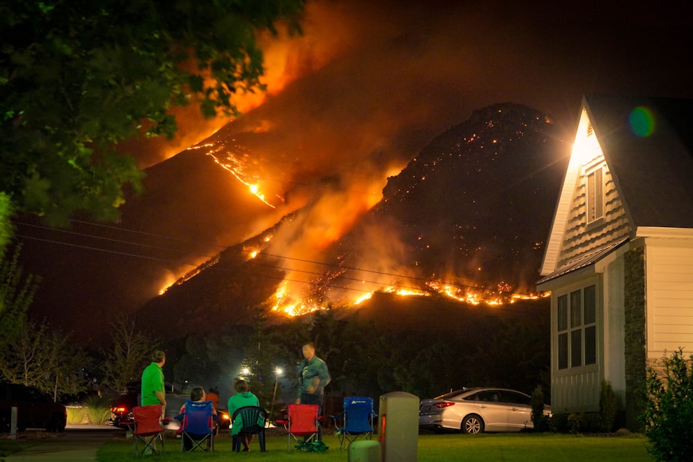 um grupo de pessoas sentadas em cadeiras de gramado na frente de um incêndio